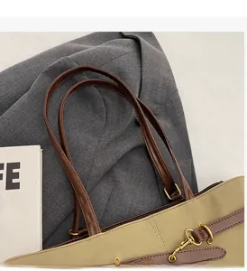 Detail of reinforced brown faux leather handles and sturdy stitching on beige tote bag