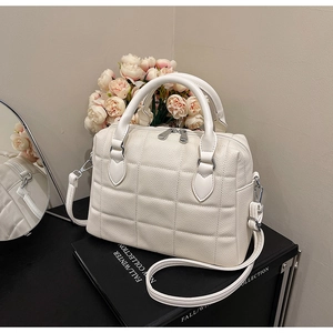 Close-up of white quilted tote bag with silver hardware and adjustable shoulder strap
