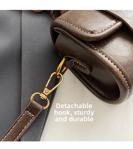 Détail du fermoir mousqueton amovible et de la bandoulière en cuir du sac Boston brun