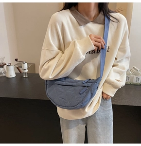 Blue quilted nylon moon bag with diamond stitch detail shown in a cozy cafe setting