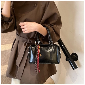 Détail du sac Boston en cuir ciré noir brillant avec rivets et breloque clé vintage