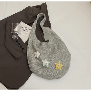 Detailstruktur der grauen Stricktasche mit drei Stern-Patches und kleinen Schleifen