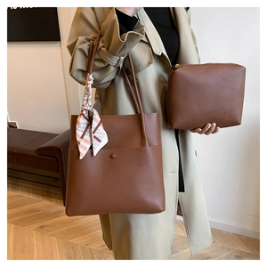 Close-up of brown lychee grain bucket bag with silk scarf detail and small inner pouch