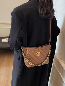 Braune Stepptasche mit goldener Kette über einem schwarzen Blazer getragen