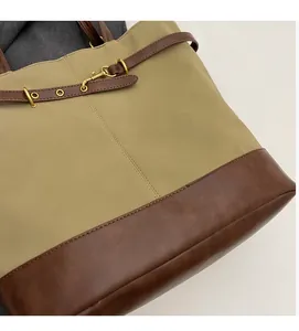 Detail of khaki canvas and brown leather stitching with gold hardware on tote bag