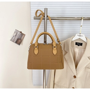 Detailed view of brown quilted Boston bag with silver hardware on a metal hanger