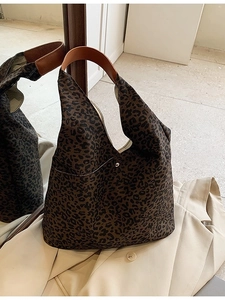 Fashionable leopard print tote bag with brown leather handles on a trench coat