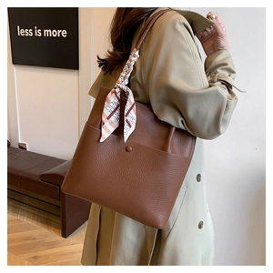 Brown pebbled leather bucket bag with a decorative silk scarf tied on the handle