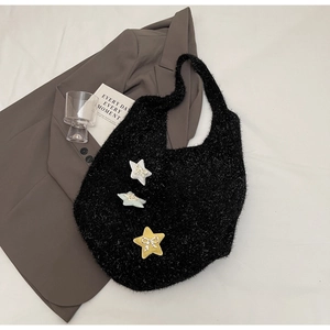 Detail der schwarzen Plüschtasche mit Sternanhängern und kleinen Schleifen auf hellem Grund