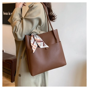 Detail of dark brown pebble leather tote bag with stylish printed silk scarf decoration