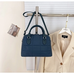 Detail of teal quilted tote bag with silver hardware and adjustable shoulder strap