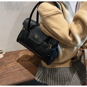 Detail of black leather tote bag with gold logo and dual handles on a model