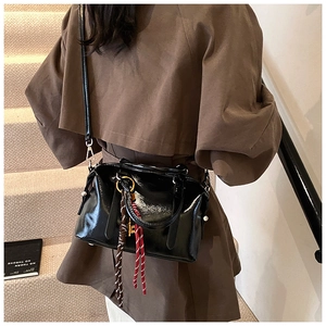 Détail du sac à bandoulière en cuir verni noir avec pendentif à franges et poignée