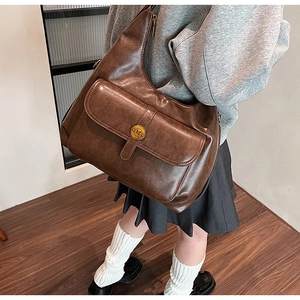 Dettaglio borsa vintage marrone con fibbia decorativa in metallo dorato lettera N