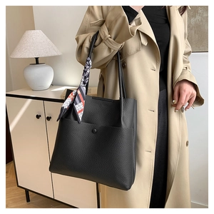 Close-up of black lychee texture tote bag with stylish silk scarf on the handle
