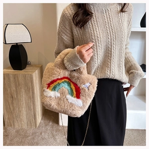 Detail of soft beige plush handbag with colorful rainbow embroidery and gold chain strap