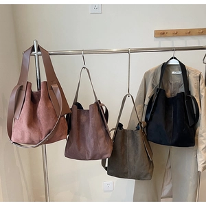 Detail view of large faux suede bucket tote bags in four trendy colors on a display rack
