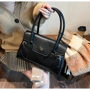 Detail of black PU leather bag showing golden metal logo and buckle with soft lighting