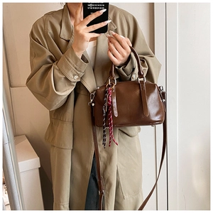 Vue détaillée d'un sac Boston marron foncé avec bandoulière tressée porté par un mannequin