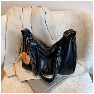 Detail of black glossy tote bag with golden hardware and cute bear pendant charm