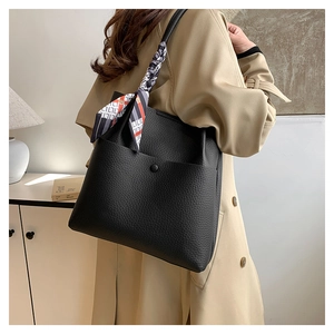 Detail of black pebbled leather bucket bag with decorative silk scarf and magnetic clasp