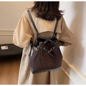 Brown canvas and black matte leather convertible tote bag worn as a backpack