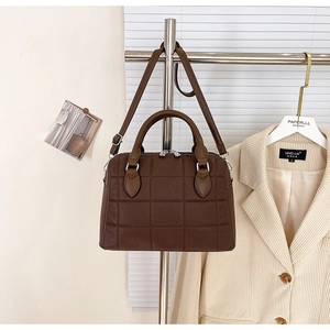 Detail view of dark brown quilted Boston bag with silver hardware on display