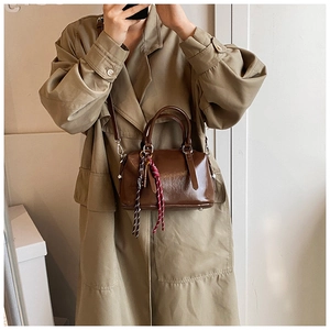 Vue détaillée du sac Boston en cuir mat marron avec cordes décoratives et bandoulière