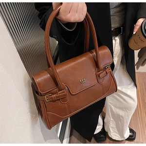 Close-up of brown faux leather shoulder bag with golden metallic logo and buckle detail