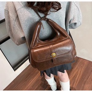 Dettaglio dello zaino vintage in pelle marrone con fibbia in metallo N e manico