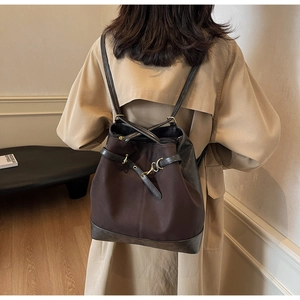 Detail of dark brown canvas backpack with black leather trim and gold metal hook