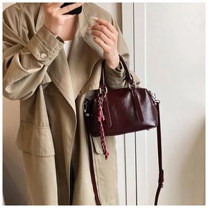 Détail du sac Boston luxe bordeaux en cuir ciré avec une sangle tressée décorative