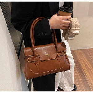 Detail of vintage brown leather underarm bag with PAN TOR logo and stylish side buckles