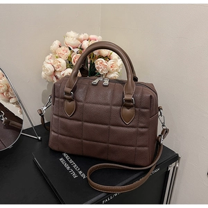 Detail view of dark brown quilted Boston bag with silver hardware and shoulder strap