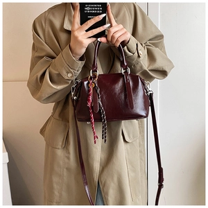 Selfie miroir d'un sac Boston en cuir bordeaux avec breloques tissées et bandoulière fine