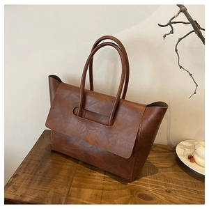 Macro shot of brown retro tote bag showing vintage leather texture on dark wood desk