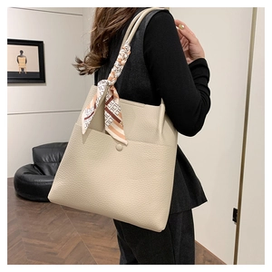 Detailed view of beige lychee textured leather bucket bag with decorative silk scarf
