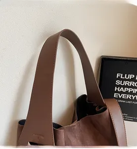 Detail of dark brown tote bag wide strap with neat stitching and matte leather texture