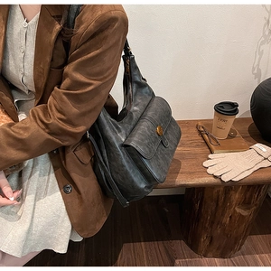 Macro dettaglio della borsa hobo nera retrò con logo metallico e tasca frontale a patta