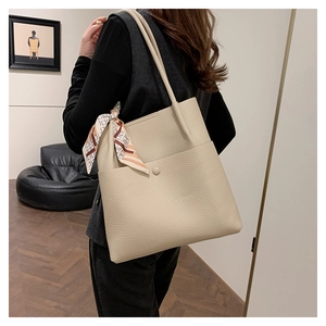 Detail of beige lychee texture bucket bag with decorative scarf and front pocket