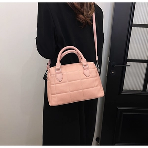 Detail view of pink lychee pattern crossbody bag with quilted squares on black suit