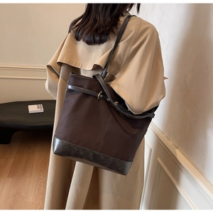 Detail of dark brown canvas tote bag with synthetic leather trim and metal eyelet belt