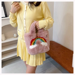 Close-up of pink plush handbag featuring rainbow embroidery and a gold chain strap