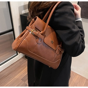 Detail view of a vintage dark brown leather shoulder bag with metallic buckle accent