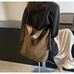 Detailed texture of brown matte suede tote bag with wide leather shoulder strap