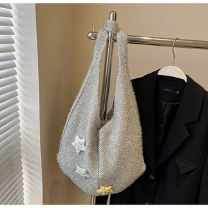 Detail der silbernen Stricktasche mit bunten Stern-Aufnähern auf gewebter Textur