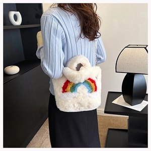 Detail of white plush shoulder bag featuring rainbow stripes and gold chain strap