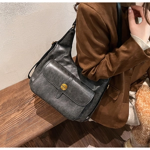 Dettaglio della borsa a tracolla retrò grigio scuro con fibbia in metallo e blazer marrone