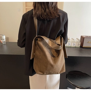 Detail of a large brown suede tote bag with a wide shoulder strap and soft structure