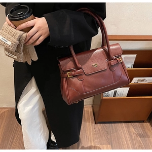 Detailed close-up of dark red leather shoulder bag with gold metal logo and handle